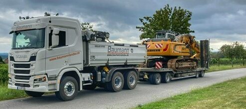 Ein Tieflader der Baumann Bautransporte transportiert einen Bagger